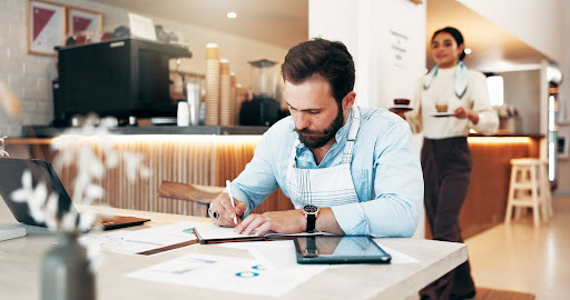 Business owner sitting at a table in his coffee shop, looking over tax documents.