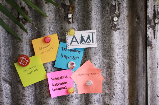 Metal bulletin board with magnets holding up sticky notes that reflect the business offerings of A.M.I. CPA Professional Corporation.