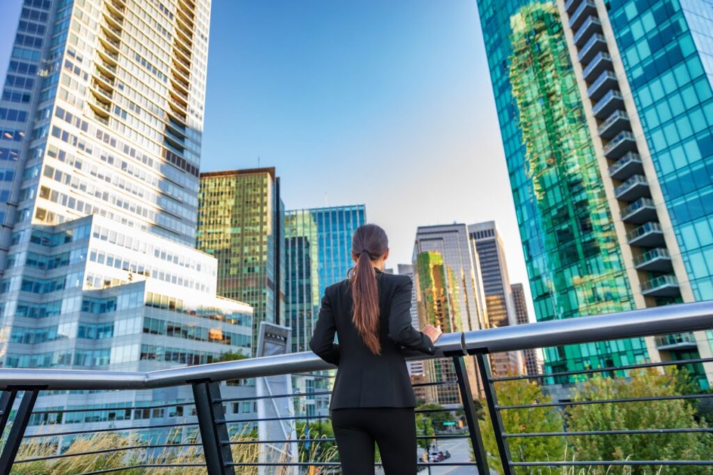 Businesswoman in the city center looking at the view of the skyline skyscrapers in Canada from the balcony of her corporate office.